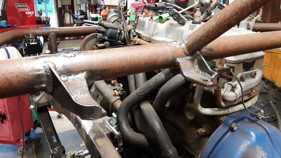 Close-up of vehicle engine and exhaust headers with custom frame welding.