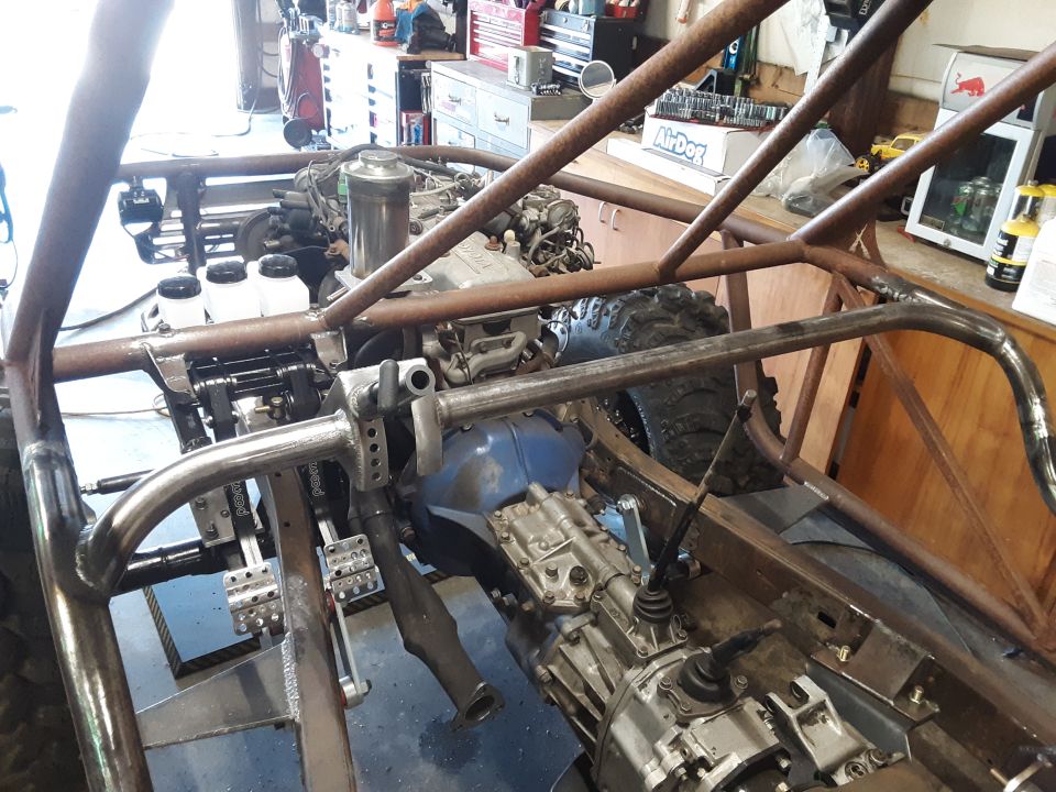 Custom buggy frame with Toyota engine and transmission, roll cage, pedals, and shifter.