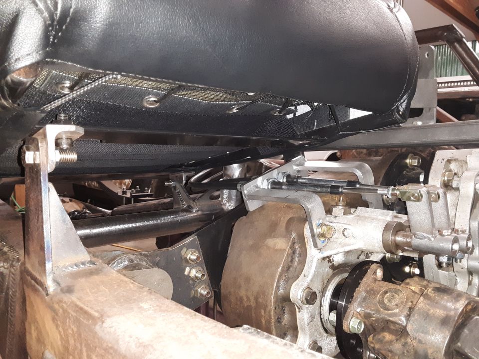 Underside of vehicle seat with mesh, connected to chassis and gearbox linkage.