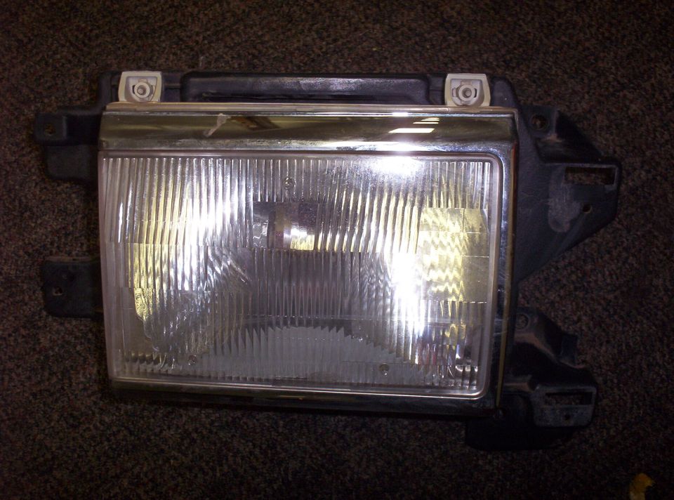 Ford Bronco headlight assembly with chrome trim and ribbed lens