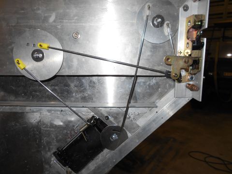 1992 Ford Bronco - Close-up view of the internal mechanism of a vehicle door, showing a door latch assembly connected to cables and pulleys. The metallic comp…