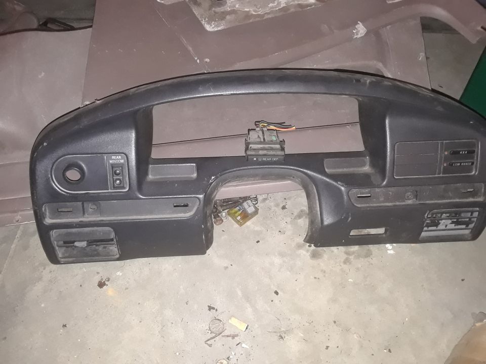 Black plastic dashboard trim with various labels for rear window, defroster, 4x4, and low range.