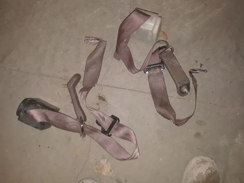 1994 Ford Bronco - A pair of seat belts, likely from a junkyard vehicle, are shown lying on a concrete surface.