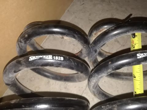 1994 Ford Bronco - Close-up of suspension coil springs, one marked "SKYJACKER 182S", with a measuring tape for scale.