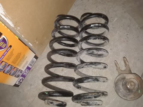 1994 Ford Bronco - A collection of coil springs and a suspension component are laid out on a concrete surface next to a cardboard box.