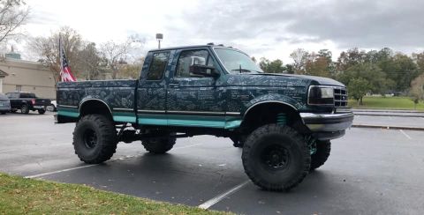 1979 Ford Ranchero - This lifted Ford pickup truck features a unique graphic wrap and is parked in a lot with other vehicles.
