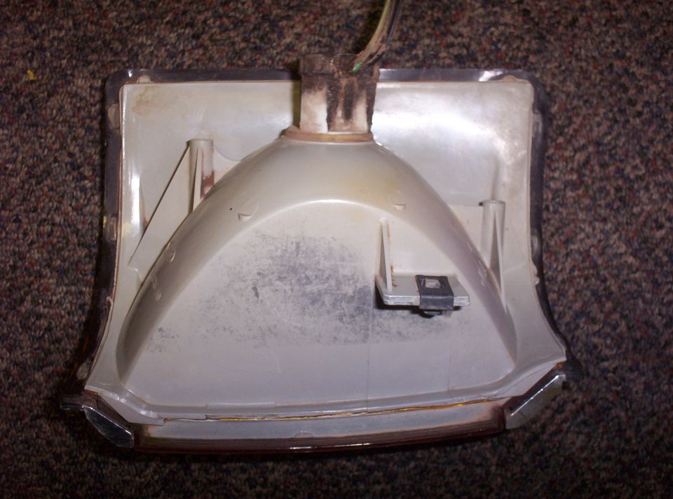 Back of a white turn signal housing with chrome trim and wires