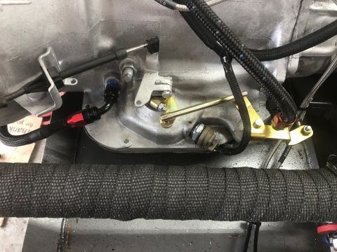1992 Jeep Wrangler - Close-up view of engine components, including a throttle cable, fuel line, and a brass linkage mechanism, with heat wrap visible on a pipe…