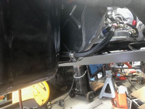 1992 Jeep Wrangler - A braided black hose with red and blue fittings is secured with a clamp to a gray metal bracket. The hose runs from a black oil pan towards…