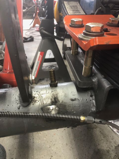 1992 Jeep Wrangler - A close-up view shows a brass fitting attached to a gray metal axle housing, with a braided metal line connected to it. In the background,…