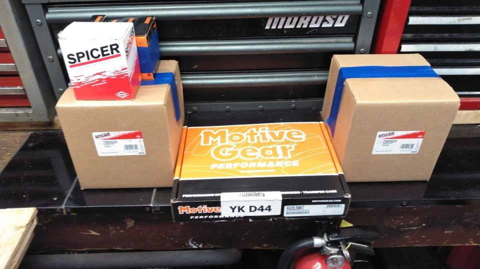 Boxes of Spicer and Motive Gear parts on a workbench.