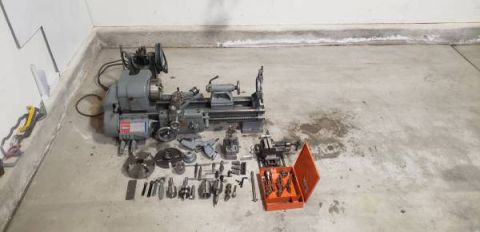 2002 Ford Ranger - A metal lathe and its associated tooling, including chucks, bits, and a drill bit set, are laid out on a concrete floor.