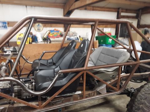 1985 Toyota Hilux - A custom-built buggy frame with racing seats is shown in a workshop setting.