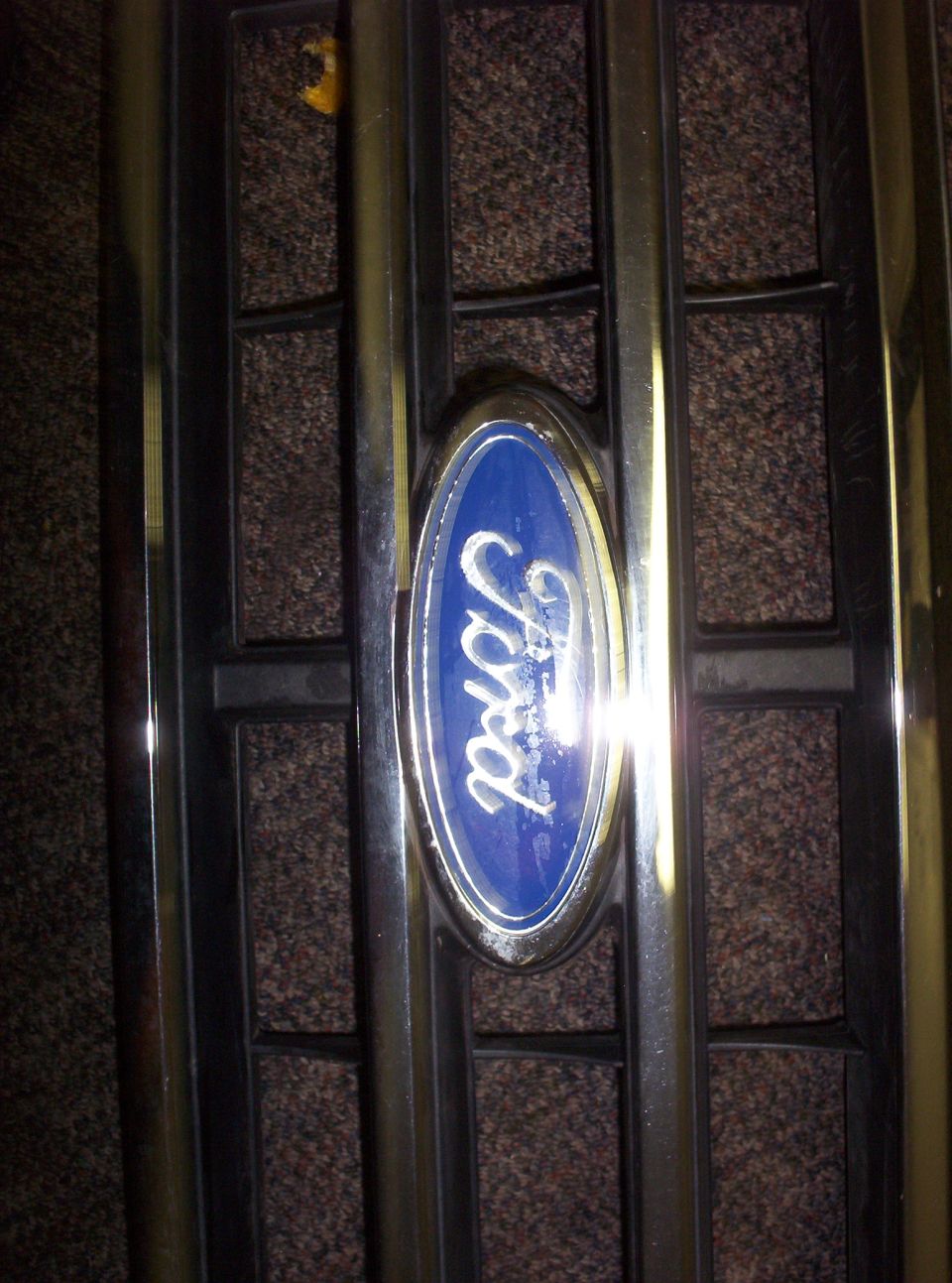 Close-up of a Ford oval emblem on a chrome grille