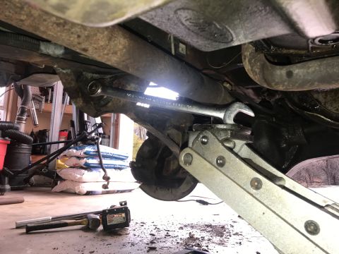 1994 Ford Bronco - Working on the undercarriage of a vehicle, using a wrench and jack to support suspension components.
