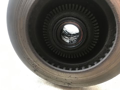 1994 Ford Bronco - Close-up view of a vehicle's wheel hub and brake rotor, showing signs of wear and grease accumulation.