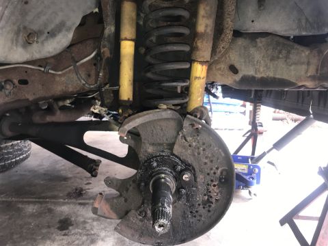1994 Ford Bronco - Front suspension component, likely a wheel hub and brake assembly, showing signs of damage.