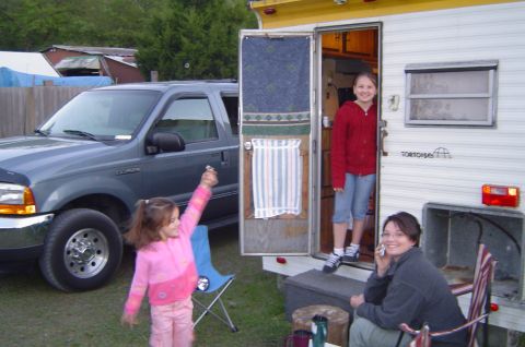 1974 Ford Bronco - A gray Ford Excursion is parked next to a camper trailer, with two young girls and a woman present.