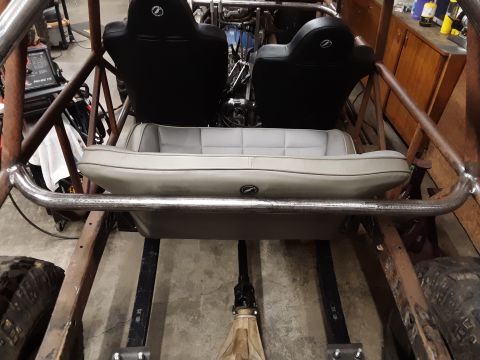 1985 Toyota Hilux - The interior of a custom buggy shows two bucket seats and a rear bench seat, with a prominent roll cage structure.