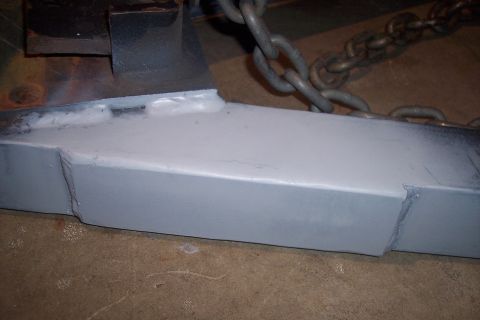 1973 Ford F-250 - A close-up view of a gray-primed metal part that has been welded and is attached to a chain.