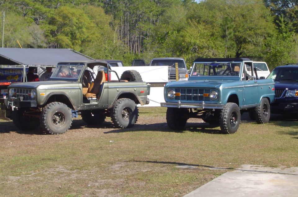 1974 Ford Bronco in green and another 1974 Ford Bronco in blue parked side-by-side