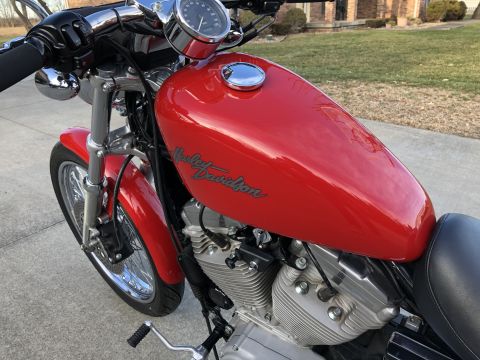 2002 Harley-Davidson Sportster Custom - A red 2002 Harley-Davidson Sportster Custom motorcycle is shown from a 3q-front perspective.
