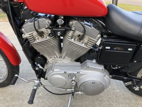 2002 Harley-Davidson Sportster Custom - Close-up of a 2002 Harley-Davidson Sportster Custom engine with a red fuel tank visible.