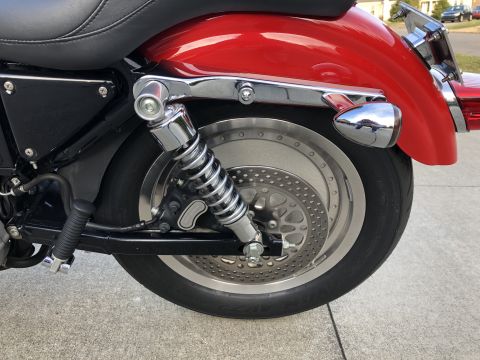 2002 Harley-Davidson Sportster Custom - The rear section of a motorcycle is shown, focusing on the wheel, brake disc, and shock absorber.