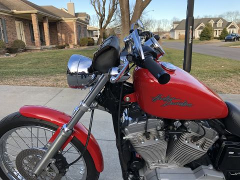 2002 Harley-Davidson Sportster Custom - A red 2002 Harley-Davidson Sportster Custom motorcycle is parked outside a residential building.