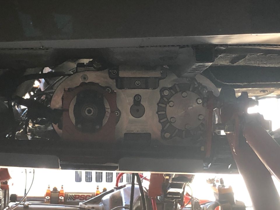 Underside view of a vehicle's transfer case and drivetrain components, with some orange accents