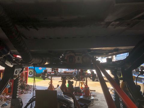 1992 Jeep Wrangler - The undercarriage of a vehicle is shown, with drivetrain components exposed and supported by jack stands.