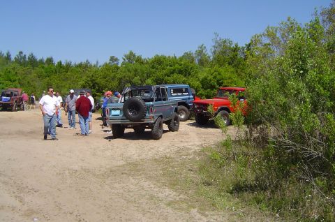 1974 Ford Bronco - Several Ford Broncos are parked at an outdoor event with people milling about.