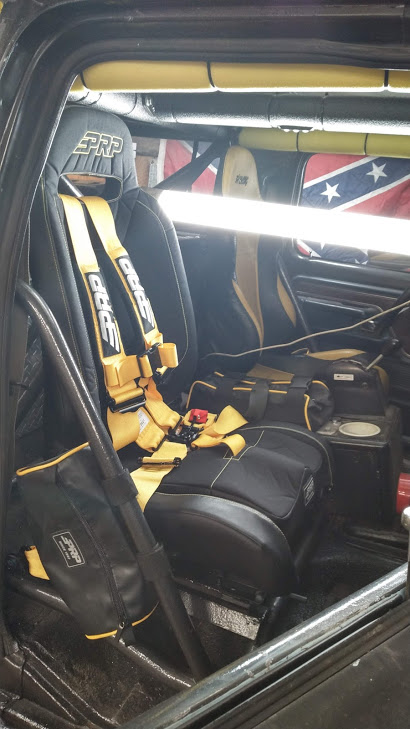 1978 Ford Bronco - Custom interior features racing seats, yellow PRP harnesses, and a roll cage, with Confederate flags visible in the background.