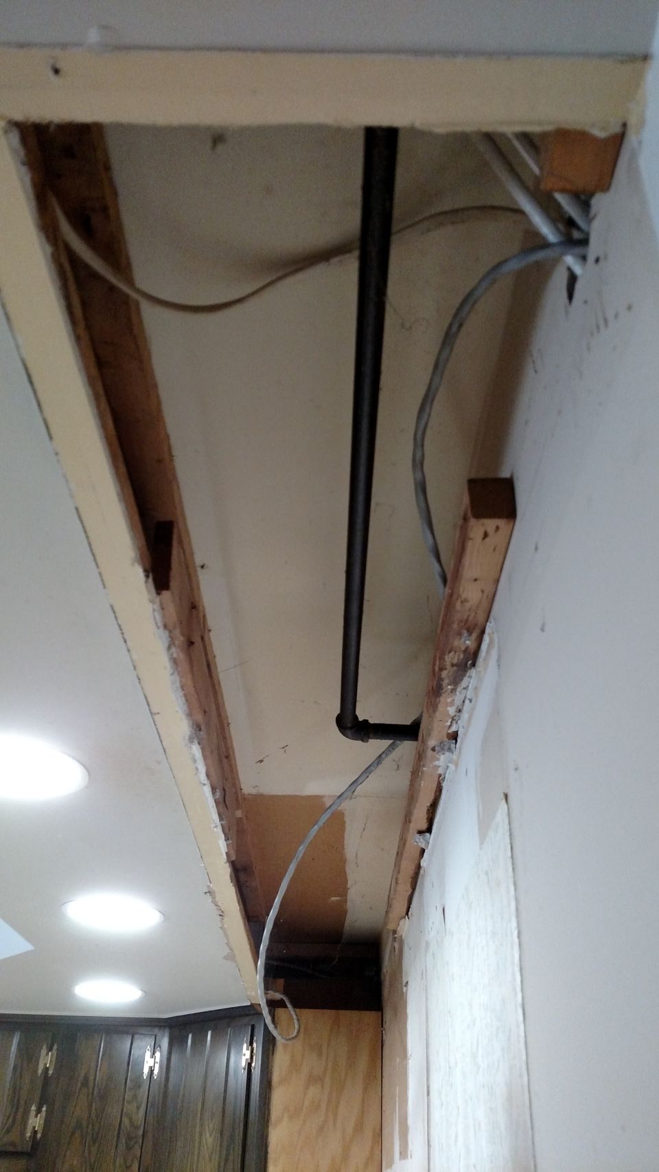 exposed ceiling joists with black pipe and electrical wires, part of a kitchen remodel
