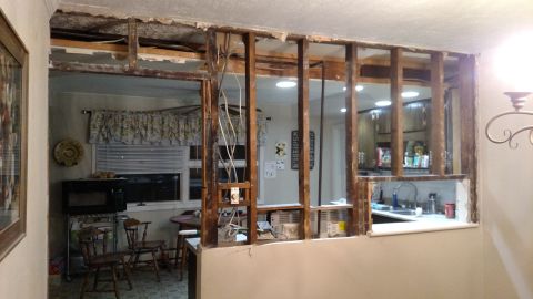 1980 Yugo Vega - Demolition work reveals the internal structure of a wall, with exposed wiring and framing in a residential kitchen.