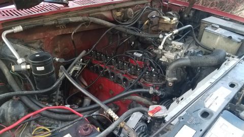 1985 Ford Bronco - The engine bay of a 1985 Ford Bronco, the V8 engine and associated parts, likely for repair or maintenance.