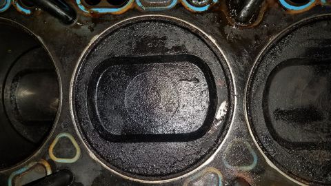 1985 Ford Bronco - Close-up of an engine's cylinder head shows significant carbon deposits within the cylinders.