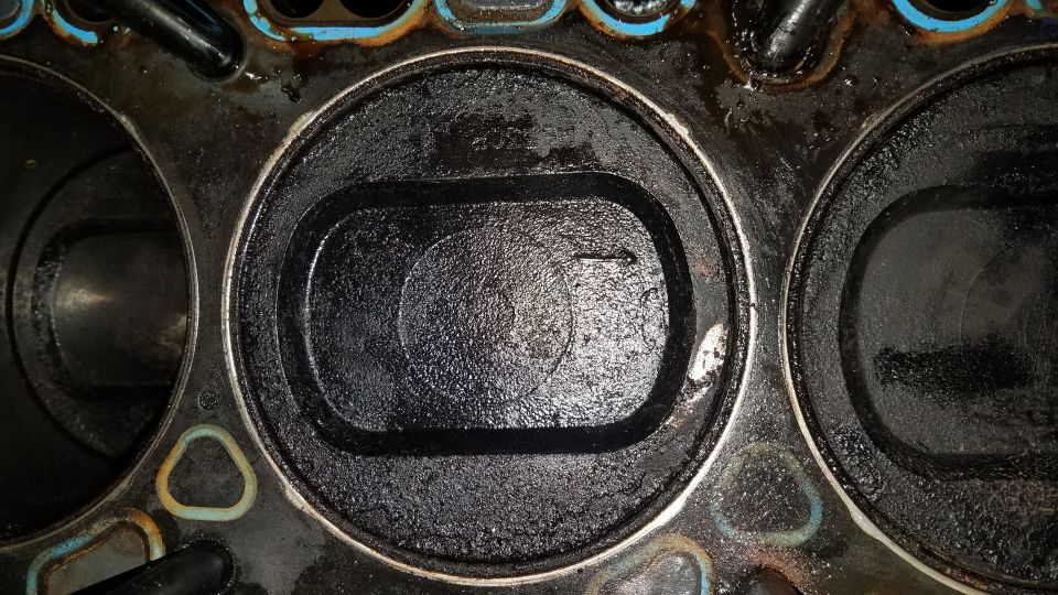 Engine cylinder head with carbon buildup in cylinders and blue gasket material
