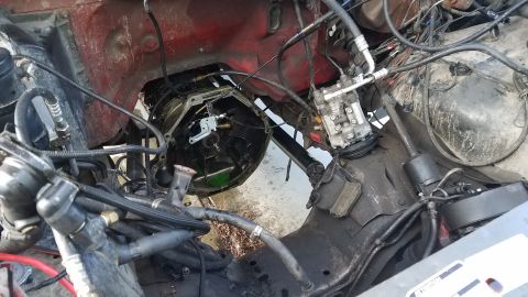 1985 Ford Bronco - Transmission bell housing area of an engine bay, transmission removed. Red firewall is visible.