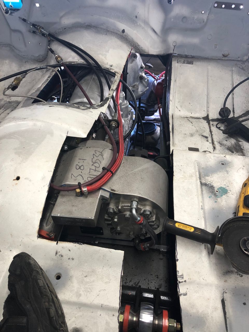 Grinder tool next to a vehicle's transmission tunnel, showing custom metalwork and wiring