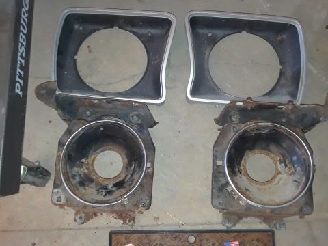 1994 Ford Bronco - Pair of headlight bezels and buckets, likely for an older vehicle, showing signs of rust.