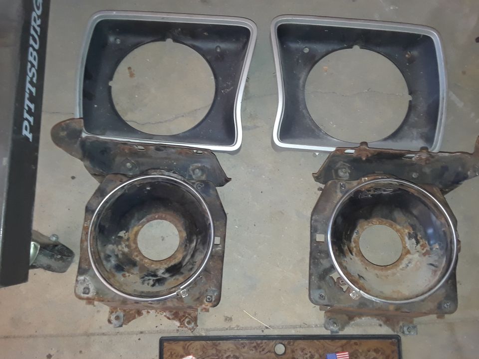 Two headlight bezels and buckets, rusty metal components