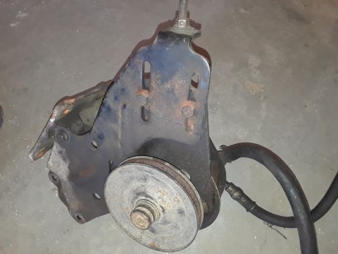 1994 Ford Bronco - This is a power steering pump bracket with a pulley and hose, likely from an older vehicle.