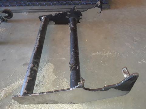 1994 Ford Bronco - A detached metal frame part, likely from a vehicle, rests on a dusty concrete surface.