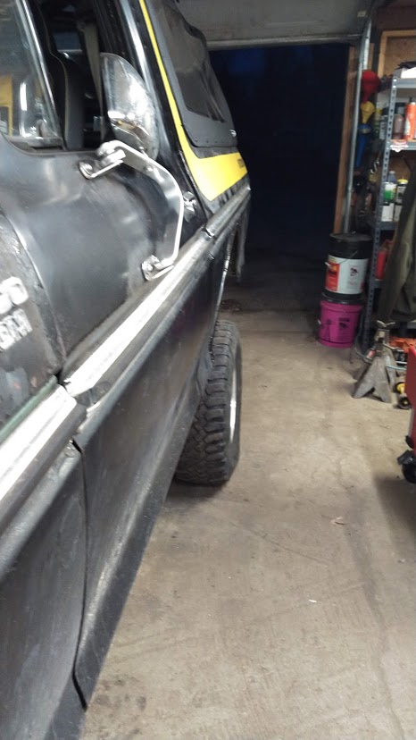 1978 Ford Bronco - The side profile of a classic Ford Bronco, captured in a garage setting with tools and shelves visible in the background.