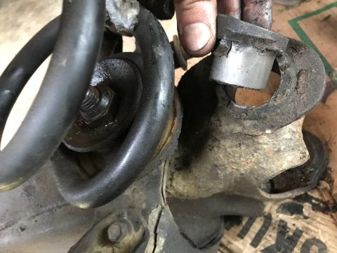 1994 Ford Bronco - Worn suspension components are shown, with a hand manipulating a metal bushing during a repair.