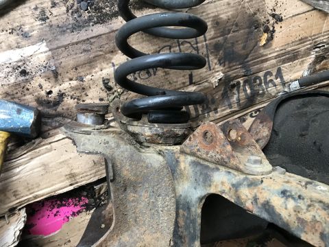 1994 Ford Bronco - Close-up of a rusty suspension component with a coil spring, possibly from a vehicle undergoing repair.
