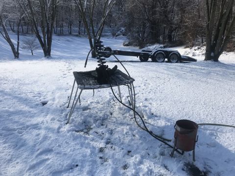 1994 Ford Bronco - A trailer sits in the snow next to a table with parts, possibly for a vehicle repair or project.
