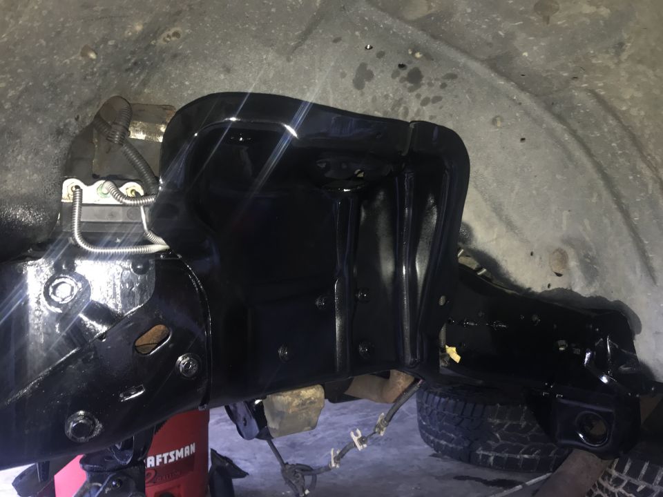 Black painted frame section with suspension parts and a tire visible