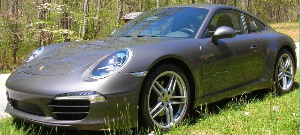 Gray 2014 Porsche 911 parked on a grassy area with trees in the background